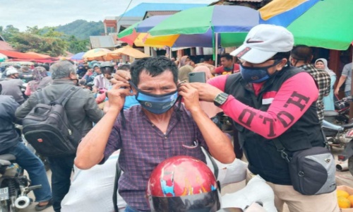 Ewin salah seorang wartawan mamasangkan masker kepada masyarakat