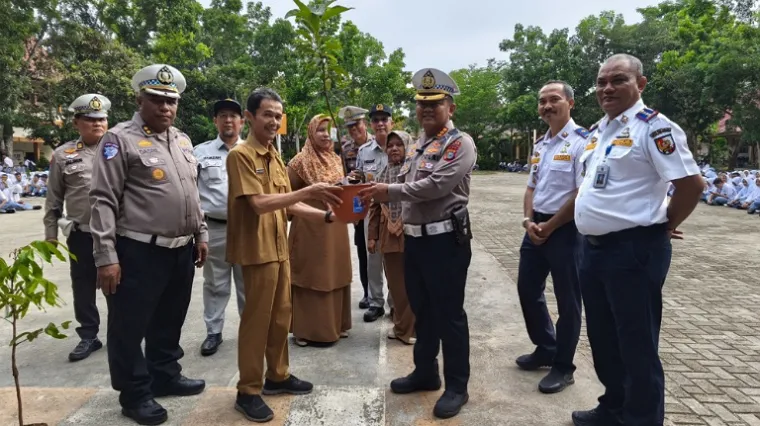 Dirlantas Polda Riau, Kombes Taufiq Lukman saat penyerahan bibit pohon kepada pihak sekolah SMKN 7 Pekanbaru