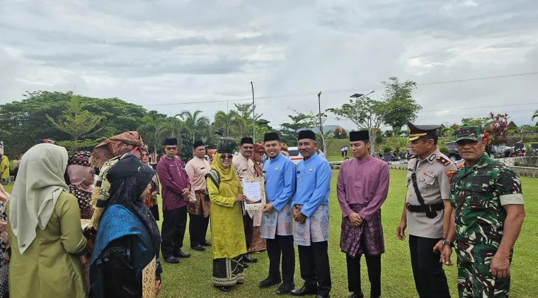 Wakil bupati Limapuluh Kota Ahlul Badrito Resha menyerahkan penghargaan kepada salah seorang guru di Hardiknas, Jumat 2 Mei 2025.