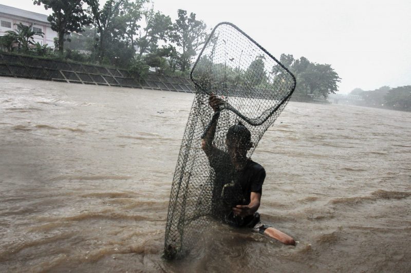 MENANGGUK IKAN | Seorang pemuda menangguk ikan di tepi banjir kanal Kota Padang, Sumbar, Senin (23/11/2020). Cuaca di Sumbar hingga 23 November 2020 masih berpotensi hujan berintensitas sedang hingga lebat disertai kilat dan petir. | Photo credit should r