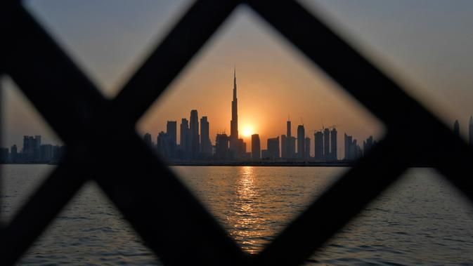 Pemandangan matahari terbenam di belakang Burj Khalifa dan gedung-gedung bertingkat lainnya, di Dubai, Uni Emirat Arab pada Sabtu (12/9/2020). (Photo by Karim SAHIB / AFP)
