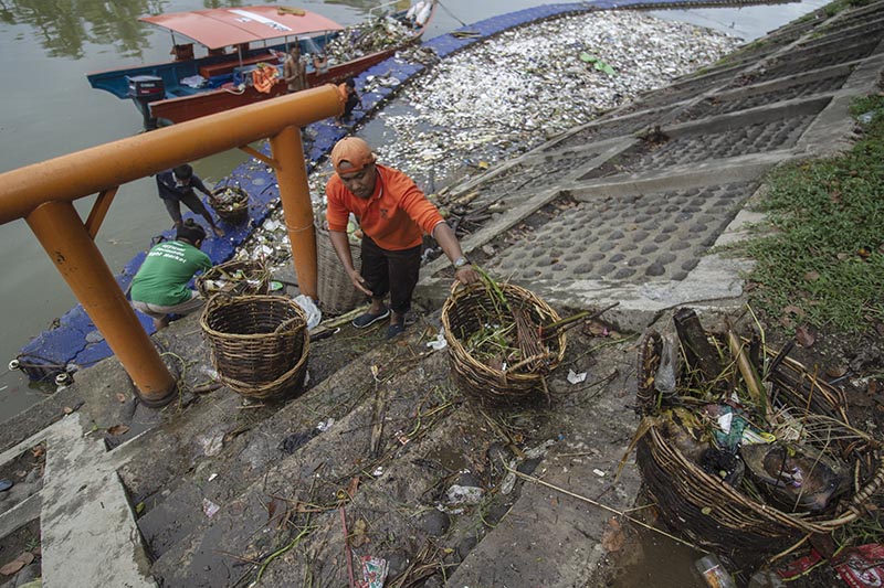 PEMBERSIHAN | Petugas kebersihan dari Dinas Lingkungan Hidup Kota Padang bersama relawan Biduak Picalang membersihkan sampah dan sampah plastik terendam air sungai yang mengalir dari sungai banjir kanal menuju pintu laut Pantai Muaro Lasak, Kecamatan Pada