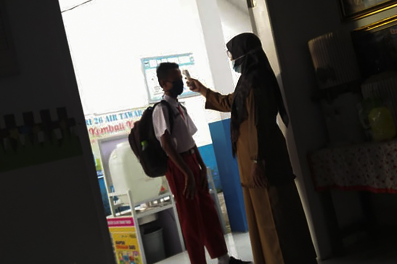 Siswa SD Negeri 26 Air Tawar Timur Kota Padang, Sumbar melewati pemeriksaan suhu tubuh yang dilakukan guru sebelum mengikuti proses belajar tatap muka yang dimulai Senin (4/1/2021). Zurna Ena/Halonusa.com