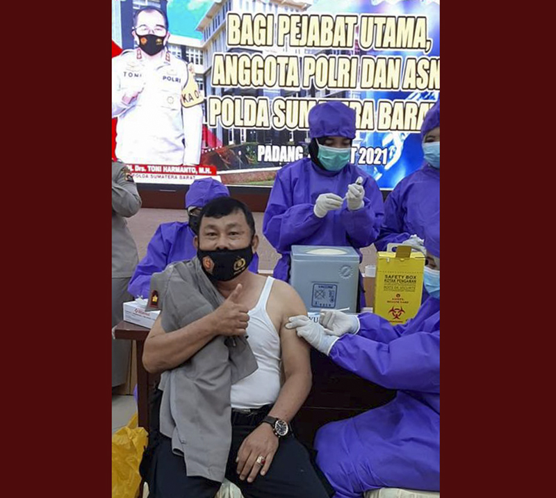 T. Harefa, salah seorang anggota Polda Sumatera Barat (Sumbar) saat menerima suntik vaksin dari vaksinator di ruang Jenderal Hoegeng lantai IV Polda Sumbar, Jalan Jenderal Sudirman, Padang, Kamis (4/3/2021). Polda Sumabar menargetkan 10.441 personel terma