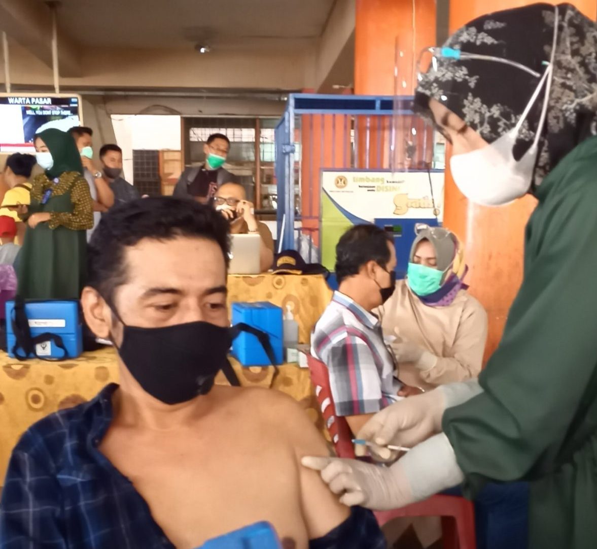 Seorang pedagang pasar di Kota Padang, Sumatera Barat menerima vaksin corona Sinovac dari vaksinator. Dinas Perdagangan Kota Padang menargetkan vaksinasi pedagang tuntas dalam tiga hari kedepan yang dimulai Kamis ini 4 Maret 2021 | Halonusa