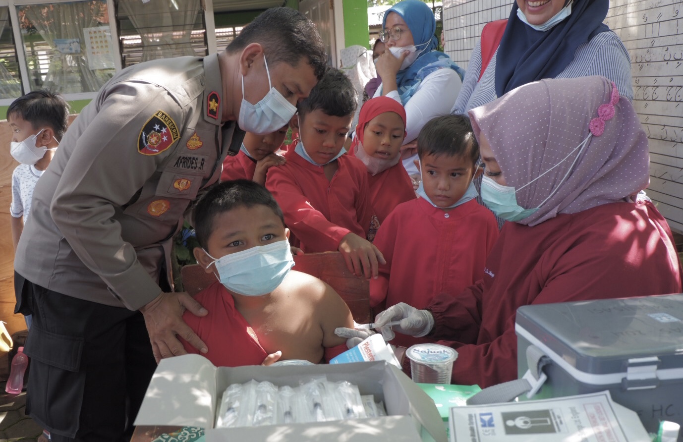 Kapolsek Padang Timur, Kompol Afrides Menenangkan seorang siswa yang melakukan vaksinasi Covid-19 di SD 32 Andalas, Jumat (21/01/2022).