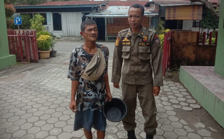 Personel Satpol PP Padang mengamankan pengemis yang berpura-pura lumpuh (Foto: Humas)