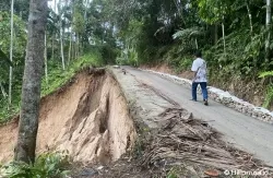 Seorang pria paruh baya melintasi jalan terban di jalan Kampuang Lansek, Silungkang, Kecamatan Palembayan, Kabupaten Agam, Jumat 26 April 2024. (Foto: Heru Candriko/Halonusa.id)