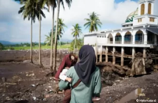 Seorang ibu yang tengah menggendong bayi dihadapan Masjid yang hancur oleh banjir bandang di Kabupaten Tanah Datar. (Foto: Instagram @iam_arianaga)